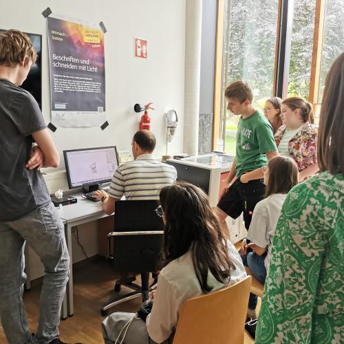 © FH Kufstein Tirol Ehrlenbach, MSc, erklärt den Schüler:innen den Lasercutter. Foto: FH Kufstein Tirol